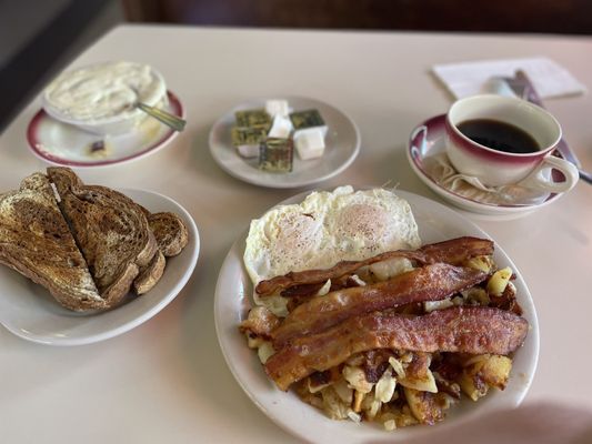 Over easy eggs, bacon, potatoes with onion, rye toast, chipped beef gravy, and coffee.