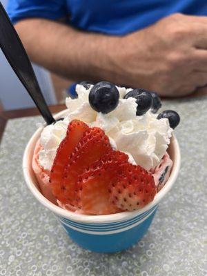 Strawberry ice cream topped with whipped cream, blueberries, and fresh strawberries