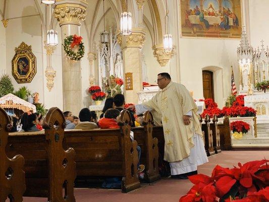 Visiting priest Father Gino of Seton Hall is asking questions to the kids during his homily