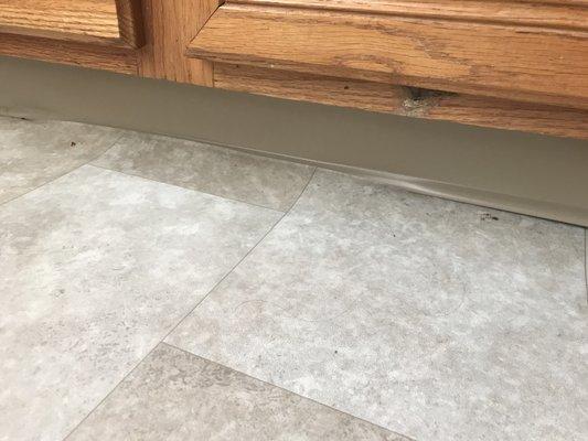 Uneven laminate flooring in the kitchen with cabinets that have seen much better days.