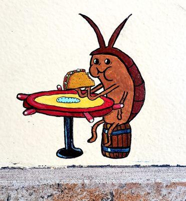 It's a tiny painting near the floor of a cockroach enjoying a taco. Very cute, random, and amusing.