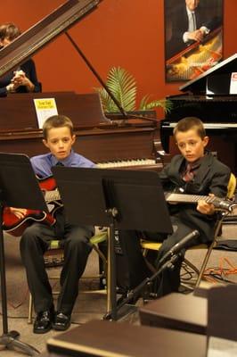 Two students playing the guitar at our Holiday Showcase.