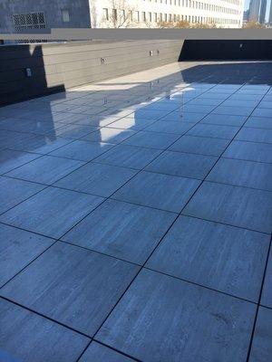 2x2 Porcelain Pavers Installed On Top Of Adjustable Pedestals. Pedestals Sit Atop Waterproof Membrane on Roof.