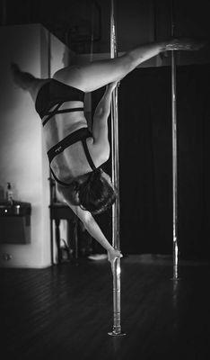 Pole dancer performing an impressive trick requiring strength and control