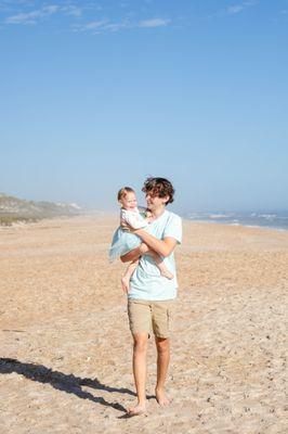 Big brother holding little sister while walking on the beach at Guana Preserve near Jacksonville, FL.