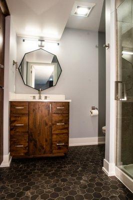 Basement bathroom with custom built cabinets, solid surface countertop, and tile shower.