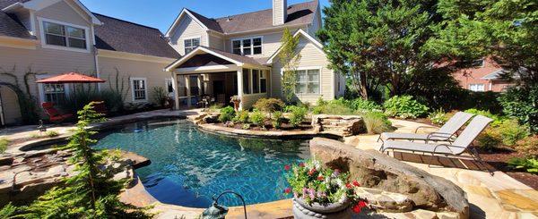 [A Burst of Color] Custom curvilinear gunite swimming pool with black bottom and stone decking.