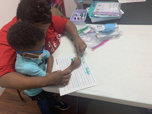 Teacher showing student how to write.