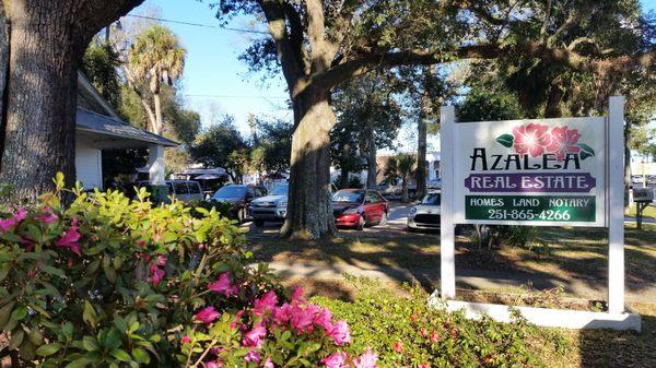 Under the canopy of the live oak, west of the Grand Bay Post Office is the office entrance