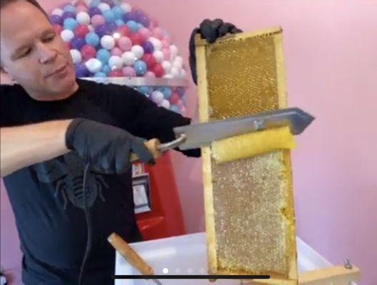 Brian uses a hot knife to remove the wax on the frames to expose the fresh honey