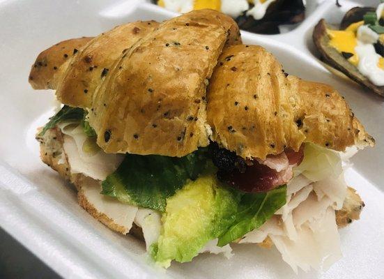 Turkey avocado sandwich- sliced turkey, Swiss cheese, lettuce and fresh avocado slices on a warm croissant