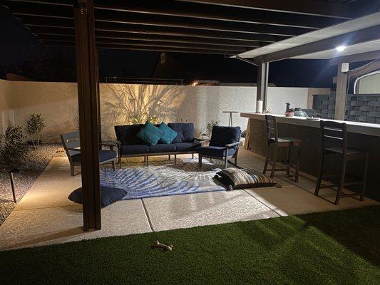 Seating area and outdoor kitchen area in one space under one patio cover.