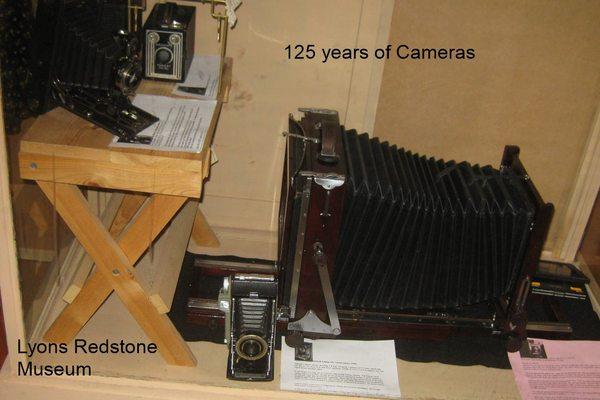 Two exhibit cases of restored cameras representing 125 years.