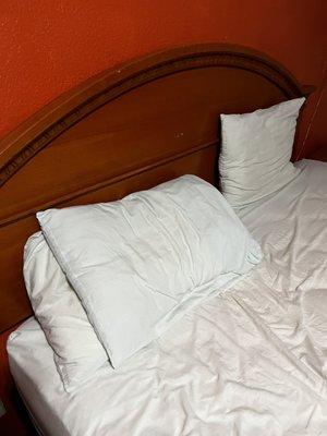 Three very flat pillows, non matching linens so thin you can see through them.