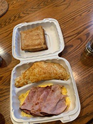 Breakfast plate with scrambled eggs, ham, potatoes, and toast