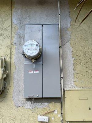 Upgraded 200 amp panel with gray stucco patching