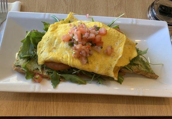 The Millenial - an omelette topped with caper relish over arugula, tomato, and avocado toast