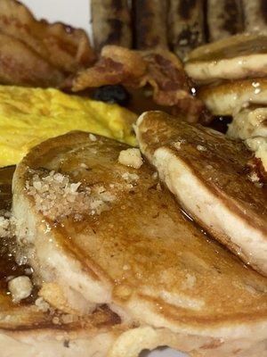 Indulge in fluffy Maple Brown Sugar Walnut Pancakes topped with caramelized walnuts, syrup. Served with French egg, bacon, and sausage.