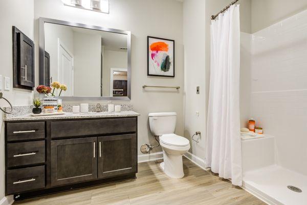 Bathroom features large mirror, sophisticated finishes, and shower with built-in shelf seat