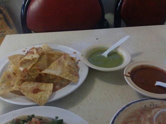 Plate of complimentary chips drizzled with queso and 2 sauces.