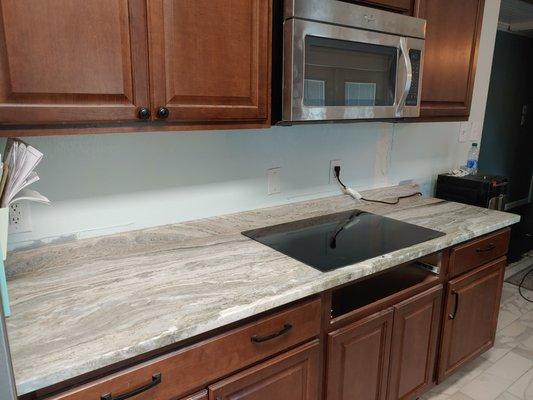 Fantasy brown granite kitchen countertops and backsplash with cooktop cutout for glass stovetop.