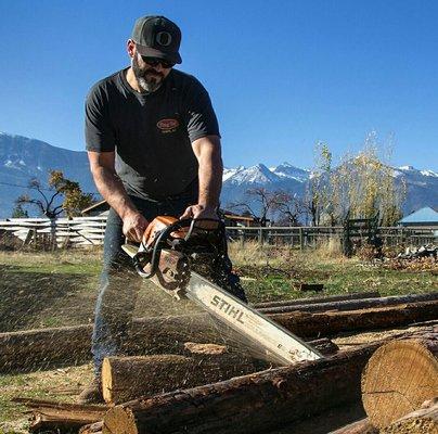 Sawing a downed tree into usable firewood. We prefer to salvage entire logs for milling but this one was better used to warm homes.