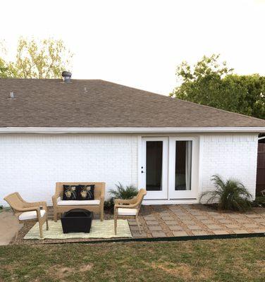 'After' back patio with new door instead of window and painted brick w/ some landscaping