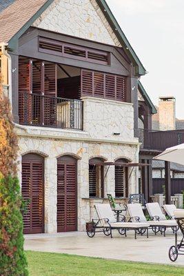 Walnut bahama and multifold aluminum shutters on exterior.