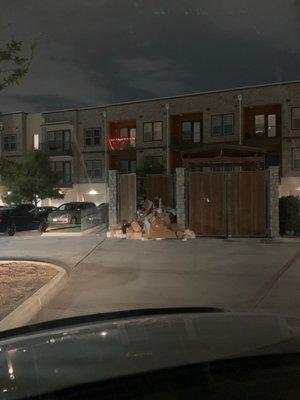 Dumpster overflowing into parking lot. This  is the FIRST thing you see when entering the gates that are stuck open wide