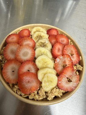 Acai bowl topped with granola, fresh sweet strawberries and bananas.. drizzled in honey.