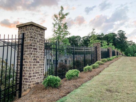 Ornamental steel fence with brick columns.