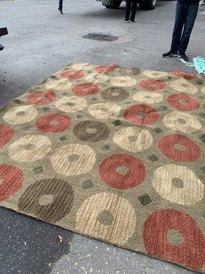 Rug laid out in parking lot of White Glove with worker of White Glove speechless.