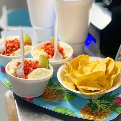 Corn in a cup with hot Cheetos on top paired with some nachos