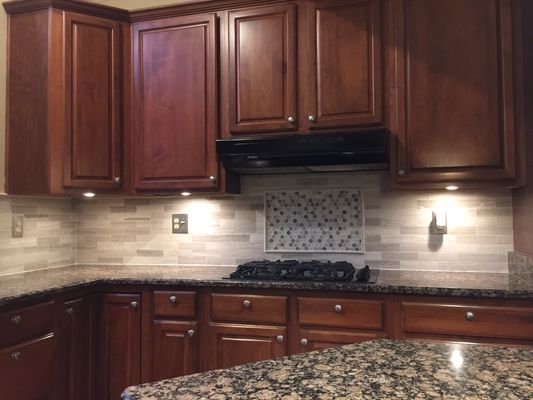 Kitchen backsplash with accented mosaic mural over cooktop