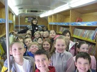 Assistance League volunteers help 1st graders check out books on Public Library Bookmobile