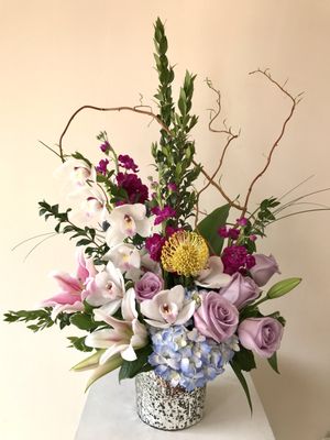 Striking Beauty is a stunning flower arrangement with orchids, lavender roses and protea.