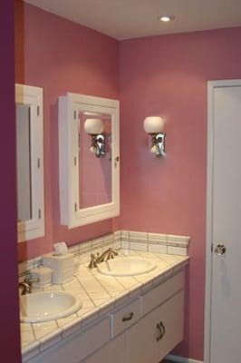 Clean makeover of a typical 70's condo bathroom using ceramic tile, new sinks, faucets and medicine cabinets & charming sconces.