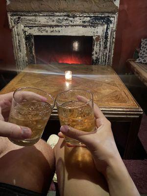 Whiskey on the rocks over a fireplace.