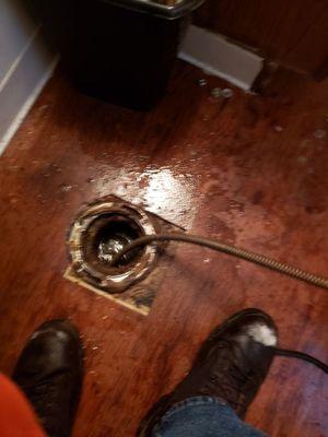 Removing a toilet to run a cable to clean out the drain.