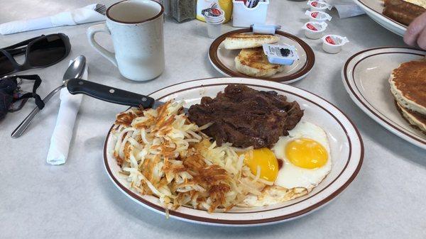 Rib-eye steak and eggs with hash browns and a biscuit