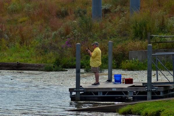 Guy looks like he's got a fish on (by boat ramp)