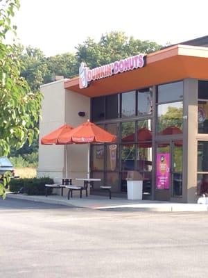 The front of Dunkin Donuts with a small area to sit and eat outside.