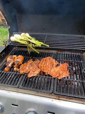 Marinated carne asada with marinated chicken legs and grilled green onions, courtesy of La Plaza...