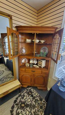 Glass Front Corner Cabinet with China and Chrystal Serving Dishes.