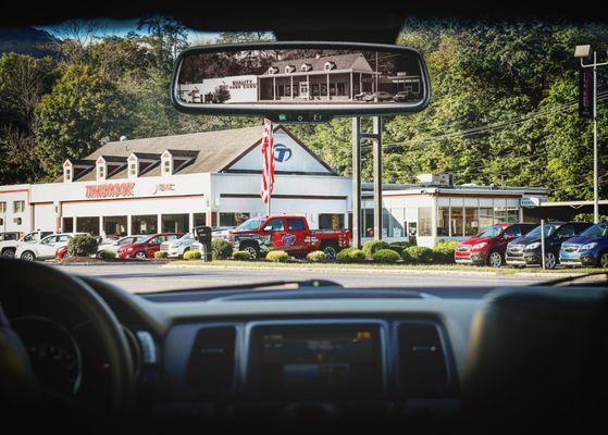 Timbrook Buick GMC through vehicle windshield with Spoerl's Pontiac Cadillac in the rear view mirror. (Flashback)