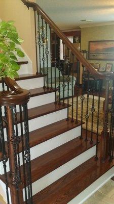 Stained oak return treads, skirt boards, Volutes and railing system with iron balusters.