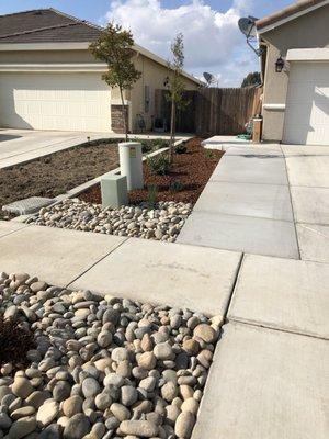 Grass was pulled out, concrete was added along with cobblestone, a tree, new plants, and lighting.