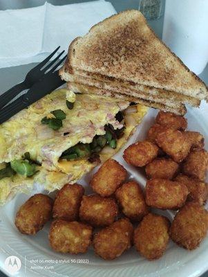 Western omelet with wheat toast and tots .