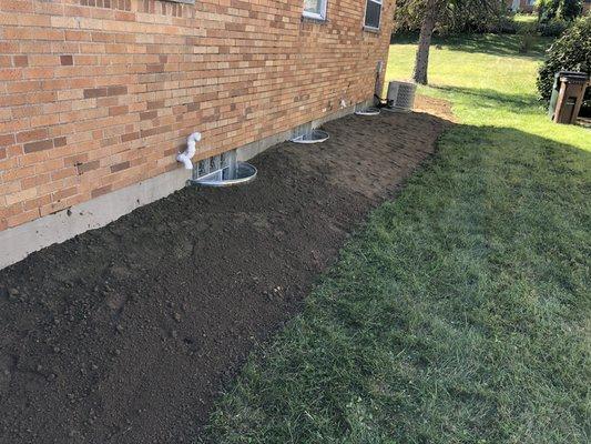 Installing Dirt around window wells to slope ground away from Home