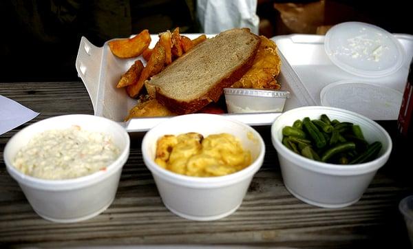 Haddock sandwich with potato wedges, coleslaw, mac & cheese, and green beans